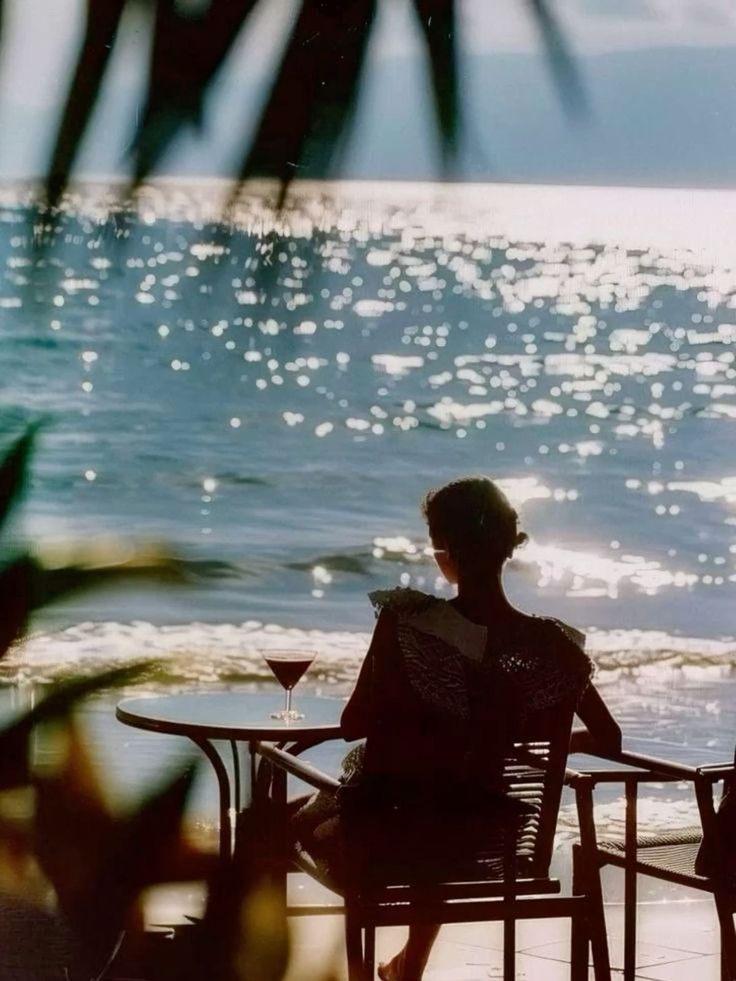 Someone seated at a café table facing a glittering sea