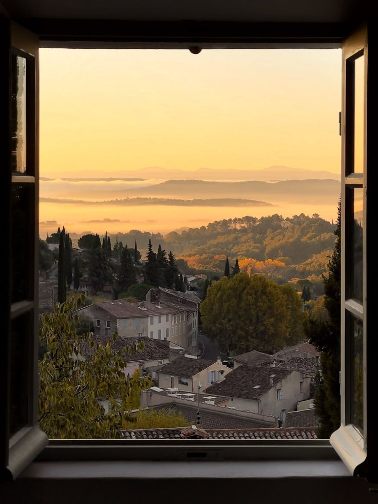 Morning light over hills and terracotta roofs, through an open window